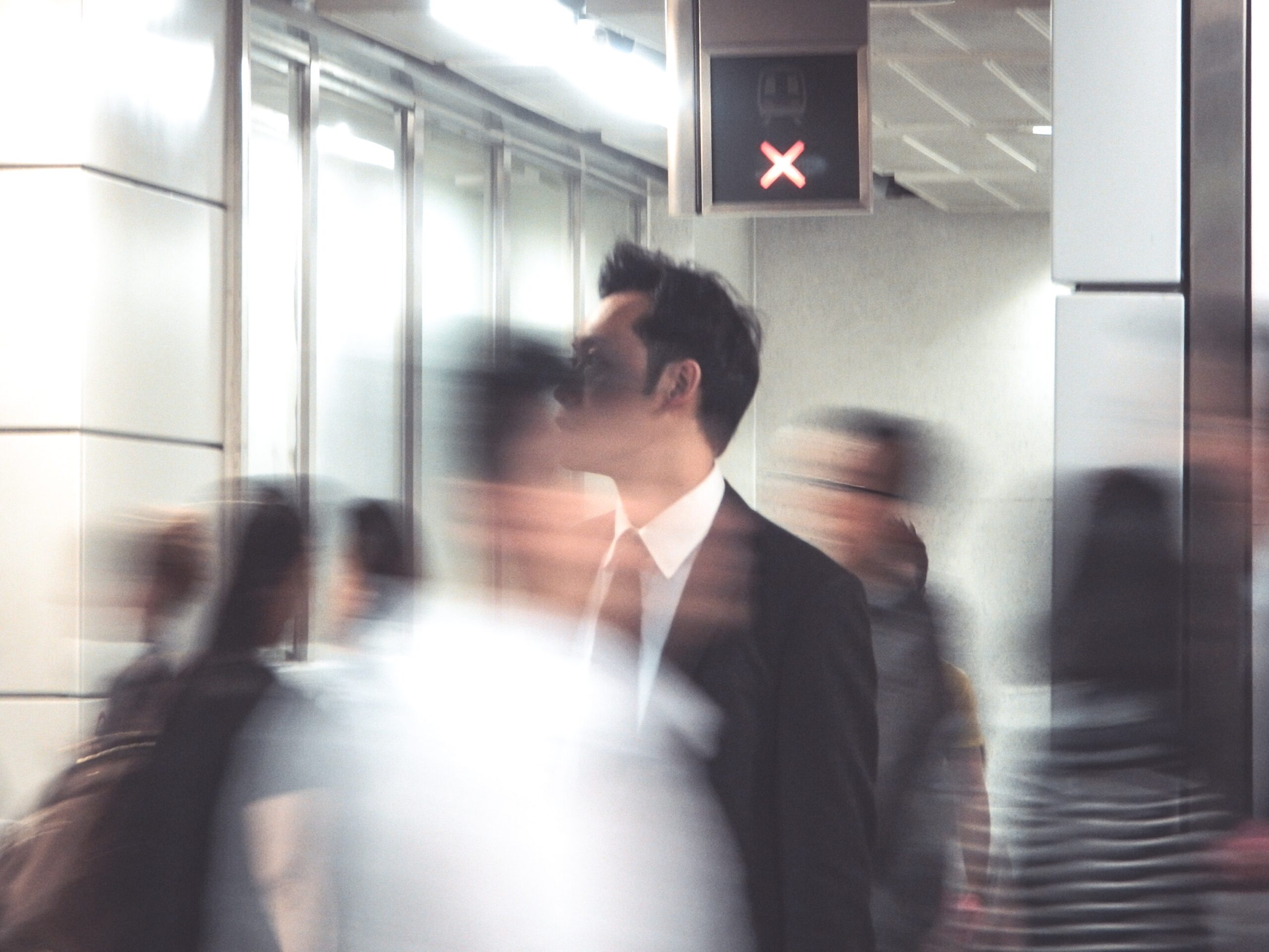 man standing and blurry images of passers by