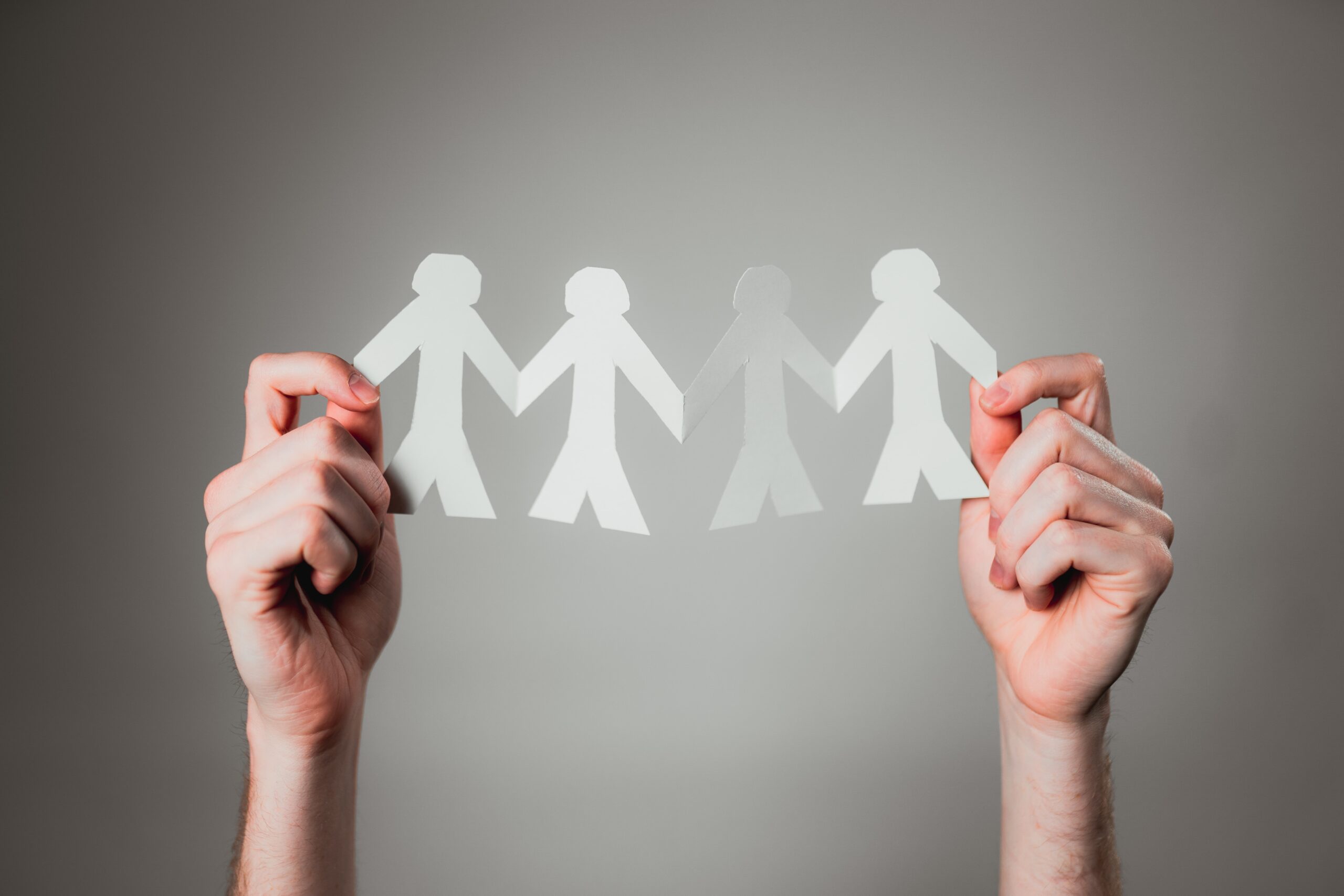 hands holding up paper cut outs of four male figures